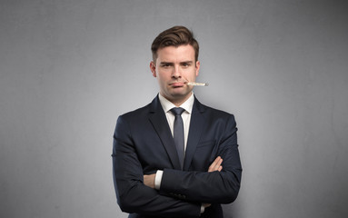 Young tired businessman with thermometer and copy space
