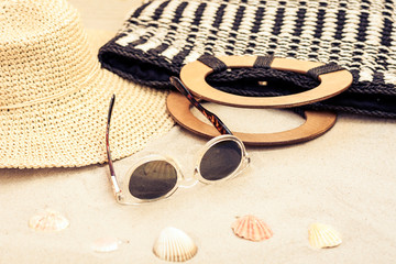 Straw hat, bag and sun glasses on a tropical beach .