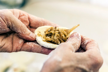 Dumplings. Dough with cabbage filling on the cook's hands.