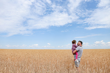 Father with his daughter in a wheat field