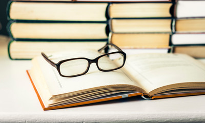 Books background, open book and glasses on white wooden table in office business background for education learning concept.