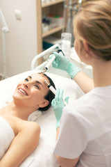 Obraz na płótnie Canvas Careful cosmetologist using prongs during the procedure