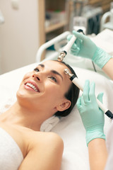Obraz na płótnie Canvas Face of happy woman enjoying facial procedure
