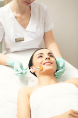 Fototapeta premium Smiling young woman enjoying peeling procedure in the clinic
