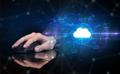 Hand using wireless mouse in a dark environment with cloud technology and online storage concept