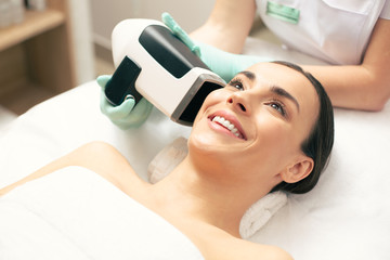 Emotional woman smiling while undergoing skin analysis procedure