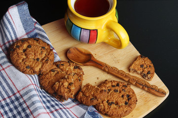 Cookies with chocolate chips and tea against dark background