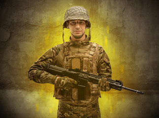 Fototapeta premium Hazard, menace soldier in a ruined crumbly building with arms on his hand 