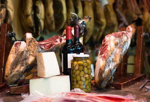 Still life of spanish pork jammon on holder, bottles of wine cheese and olives