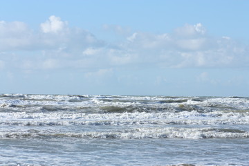 Waves in the sea and cloudy blue sky.