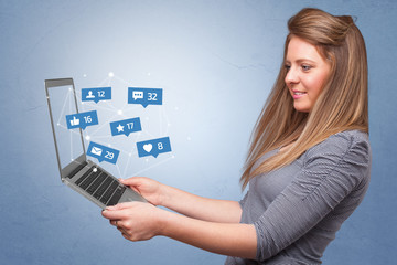 Woman holding laptop with different types of social media symbols and icons

