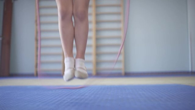 A close-up of a young gymnast jumping with the rope in the gymnastic hall