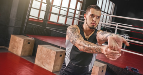Warm up before training. Close-up of young muscular athlete in sports clothing warming up before training in boxing gym