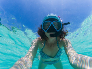 woman taking an underwater selfie while snorkeling in crystal clear tropical water