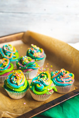 beautiful, bright, very colorful muffins decorated with rainbow cream and candy confetti, on a bright, spring background