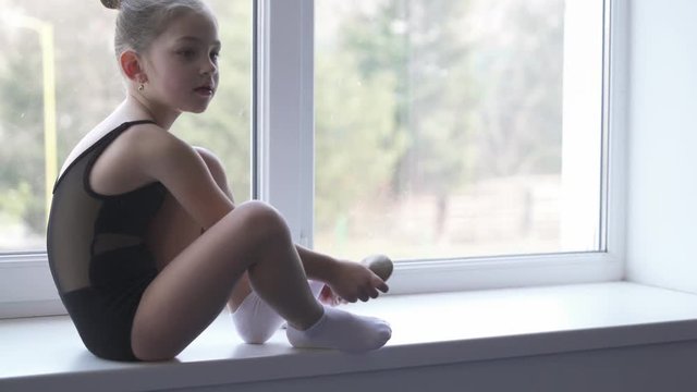 A demonstration video of a young girl wearing white rhythmic gymnastics shoes before training