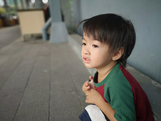 The boy is sitting in a public place.