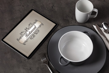 Tablet with stylish restaurant logo and laid table
