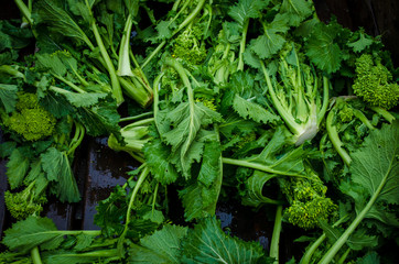 Dettaglio di alcune cime di rapa accatastate sul banco di un mercato in Puglia