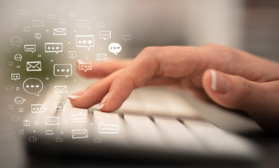 Business woman hand typing on keyboard with chat icons around