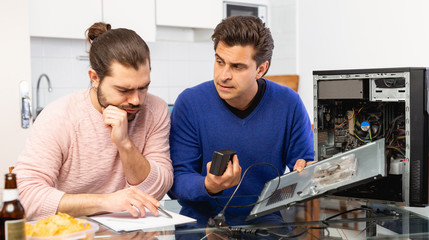 Men drink beer and repair the desktop computer