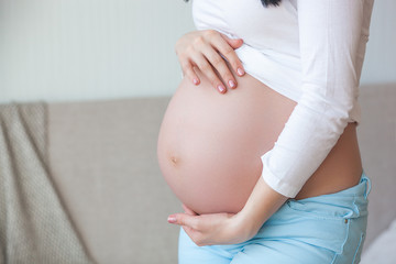 Young pregnant woman indoors. Closeup portrait of woman expecting. Beautiful female waiting for her little baby birth.