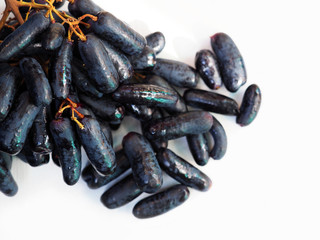 Witch fingers or black seedless moon drops grape on white background, close-up. Bunch of fresh sweet black sapphire grape