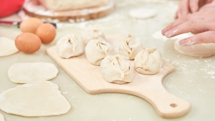 Fototapeta na wymiar Uzbek national food manta, like dumplings, puts ingredients with a man's hand. selective control focus
