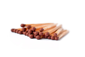 Pile of wooden matchsticks with brown heads isolated on white background