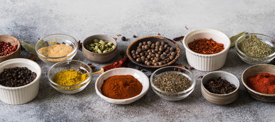 Various dry spices in small bowls on gray background. copy space