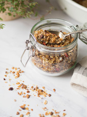 Nuts, seeds, goji berries granola in open glass jar. Healthy breakfast - homemade granola in a jar on a marble white background