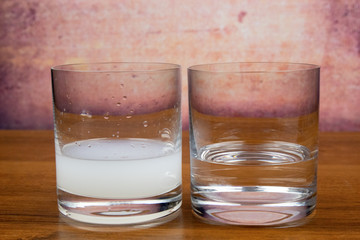 Two glasses with sambuca, in one a clean sambuca, in the other one diluted with water