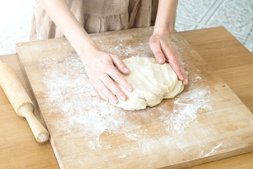 female hands knead the dough on a wooden board cooking baking.