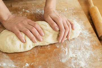female hands knead the dough on a wooden board cooking baking.