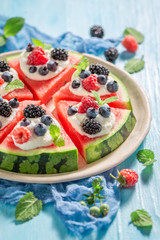 Fresh watermelon pizza with berries, whipped cream and mint leaves