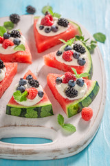 Delicious watermelon pizza with berries, whipped cream and mint leaves