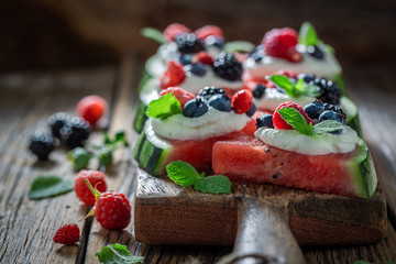 Healthy watermelon pizza with berries, whipped cream and mint leaves