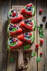 Tasty watermelon pizza with berries, whipped cream and mint leaves