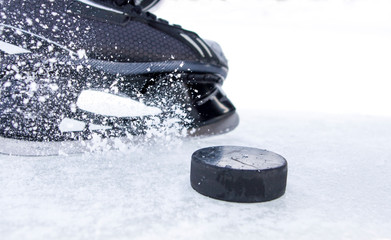 hockey skate with snow splashes and puck