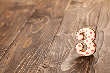 number three on a wooden background. gingerbread with frosting.