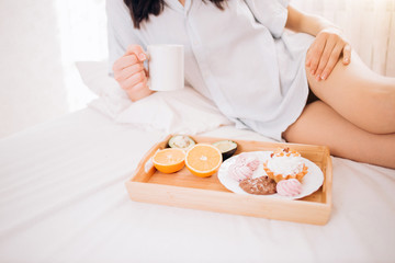 Obraz na płótnie Canvas Young woman eating healthy breakfast in bed