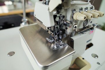 Closeup view of details of sewing machine at garment factory. Horizontal color photography.