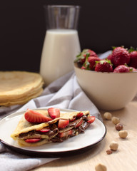crepes with strawberries and chocolate cream, black background