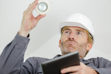 happy electrician installing a lightbulb