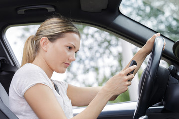 Fototapeta na wymiar woman driving car and texting message on smartphone