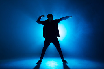 Leisure, lifestyle, hobby and sport. Professional male dancer dancing in night club with smoke and blue neon lights with flare in centre