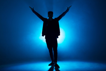 Full-size of silhouette of male break dancer performing on blue neon stage his expressive dance,...