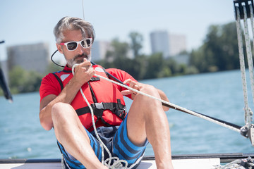 mature man pulling on rope of sailing vessel