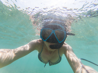 Fototapeta premium woman taking an underwater selfie while snorkeling in crystal clear tropical water