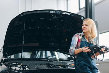 smiling awesome pensive girl looking aside while scanning a car. close up photo. copy space